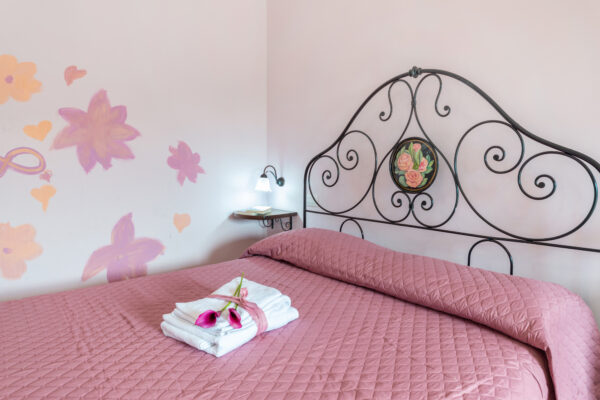 Letto matrimoniale in ferro battuto e parete con decorazioni floreali nella Camera Colle della Collina del Nido del Falco a Montefalco