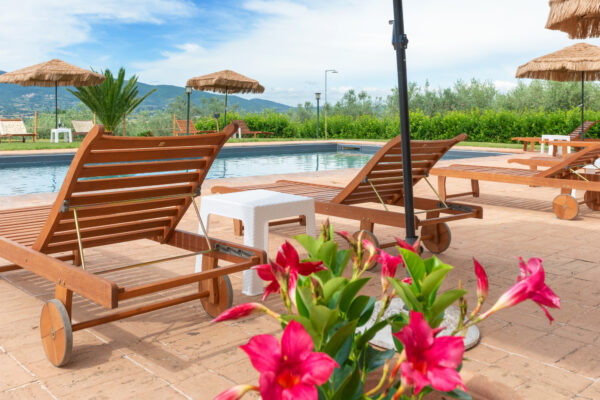 Lettini in legno e fiori a bordo piscina al Nido del Falco a Montefalco