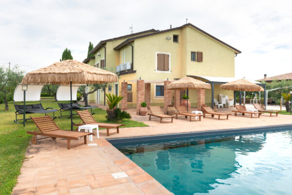 Piscina con lettini e ombrelloni davanti all’affittacamere Il Nido del Falco a Montefalco