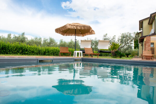 Acqua della piscina con ombrellone e lettini sullo sfondo al Nido del Falco a Montefalco