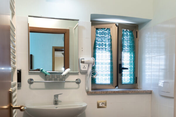 Lavabo, specchio e finestra nel bagno della Camera Vigna Antica