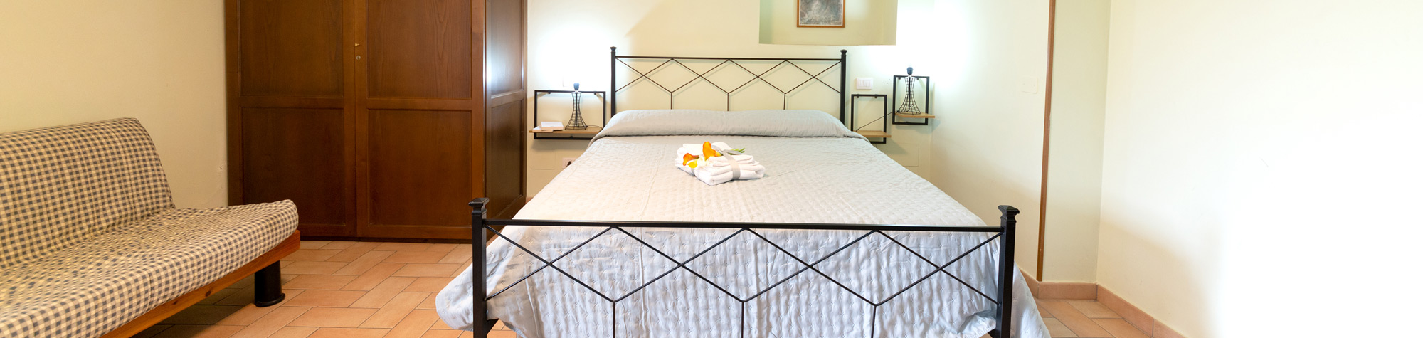 Vista panoramica della Camera del Tramonto con letto matrimoniale, divanetto e armadio in legno